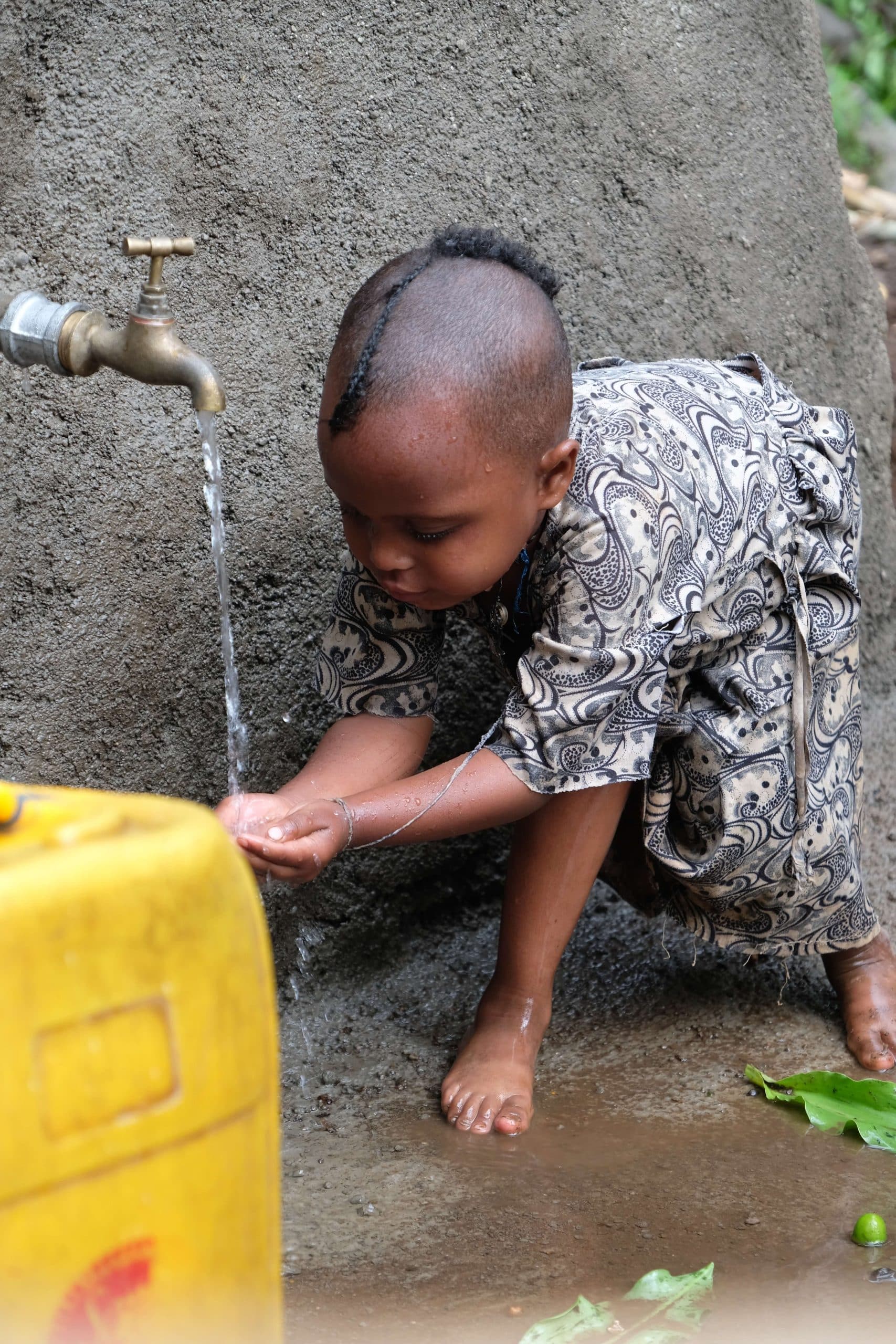 Child washing hands under clean water