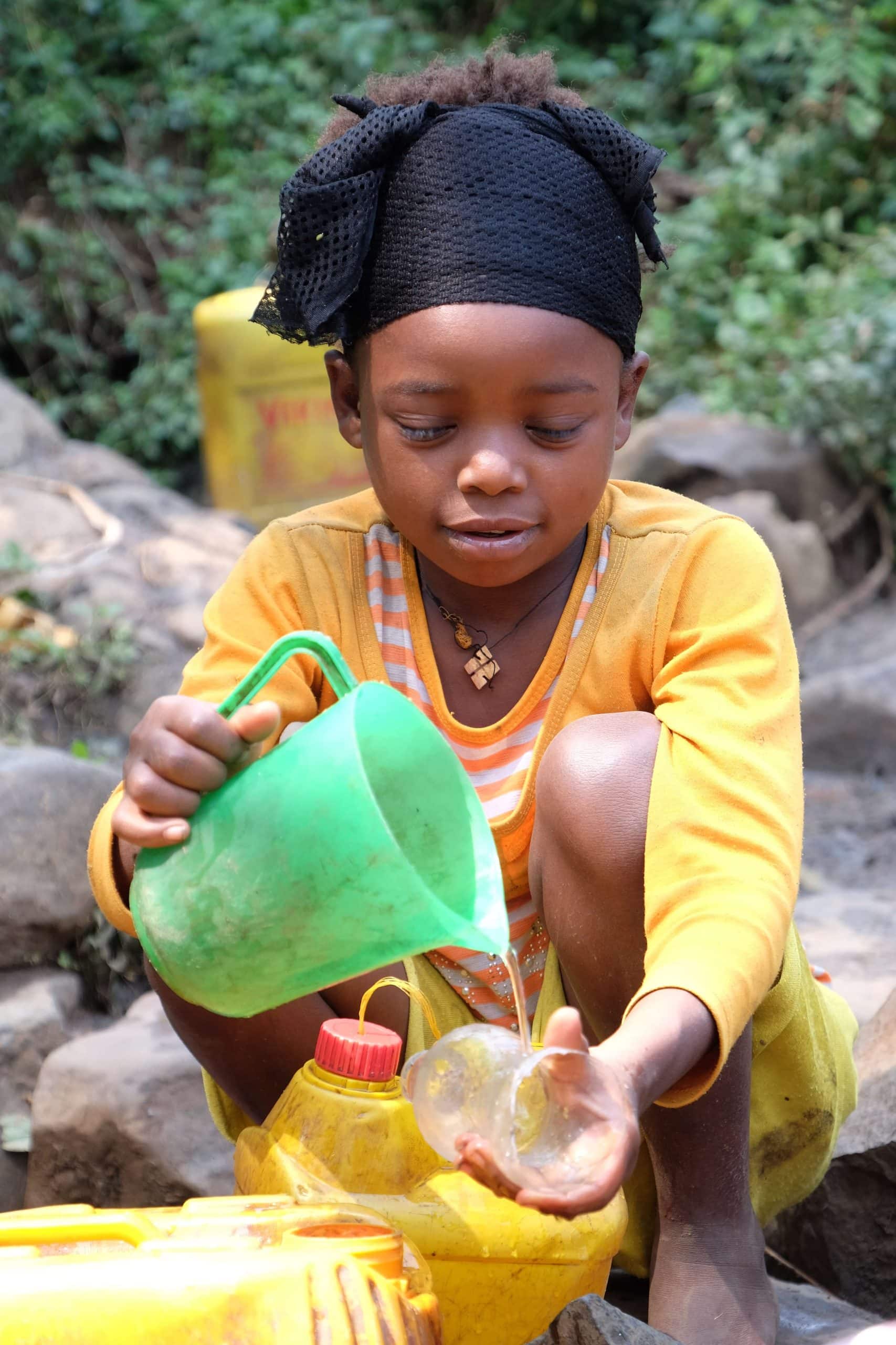 Girl using green jug to pour water